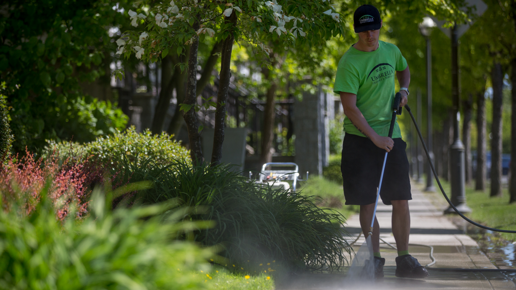 An umbrella employee pressure washing a driveway - Umbrella Property Services